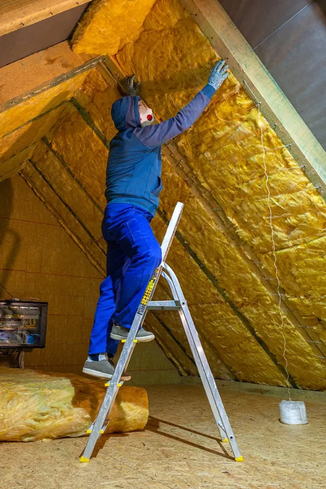 Artisan posant de l'isolant dans des combles